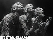 The black and white photo depicts three figurative zombies, stretching their arms towards the sky. Their emaciated, withered bodies and wrinkled faces, expressing despair or prayer, create a powerful dramatic mood. Detailed elements of clothing and skin textures add depth to the image. The black background enhances the contrast and focuses attention on the main characters. This photo is perfect for use in horror, mysticism, post-apocalyptic themes or conceptual art projects. Стоковое AI-изображение, AI-художник Анна Кривицкая / Фотобанк Лори