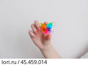 Детская зубная пластина радужного цвета. Ребенок держит в руках ортодонтическую пластинку, чтобы выровнять зубы и расширить челюсть. Стоковое фото, фотограф Терехова Марина / Фотобанк Лори
