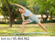 Woman practicing yoga in garden, performing Anjaneyasana, or Crescent Moon Pose. Стоковое фото, фотограф Яков Филимонов / Фотобанк Лори