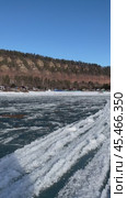 Vertical video of Siberian river Irkut in November during freeze-up on sunny day. Ice floes float on water. On shore is Shamanka village near famous Shamansky cliff, called 33 heroes bogatyrs - natural landmark. Стоковое видео, видеограф Виктория Катьянова / Фотобанк Лори