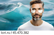 A man with hydrogel eye patches under his eyes stands against a blue ocean wave backdrop, symbolizing skincare and freshness. Стоковое AI-изображение, AI-художник Igor Tichonow / Фотобанк Лори