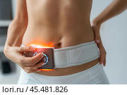 Woman using ems electronic muscle stimulator belt for abdominal fitness training. Стоковое AI-изображение, AI-художник Иван Рябоконь / Фотобанк Лори
