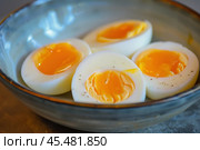 Soft boiled eggs with runny yolks sprinkled with black pepper in bowl. Стоковое AI-изображение, AI-художник Иван Рябоконь / Фотобанк Лори
