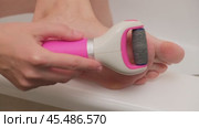 Close-up of person using an electric foot file to remove calluses from the foot. Personal care and hygiene concept. Design for healthcare, beauty, and skincare promotion. A woman of 40 years old. Стоковое видео, видеограф Андрей Журавлев / Фотобанк Лори