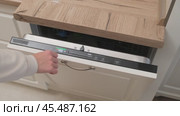 Hand pressing eco mode button on built-in dishwasher control panel. Kitchen appliance close-up with wood countertop. Energy-saving and household technology concept. Стоковое видео, видеограф Андрей Журавлев / Фотобанк Лори