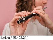 Close-up of hands playing a piccolo flute on a pink background. Studio photography for music and instrumental concepts. Стоковое фото, фотограф Андрей Журавлев / Фотобанк Лори