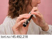 Close-up of hands holding a piccolo flute against a pink background. Studio shot for musical themes and instrumental concepts. Стоковое фото, фотограф Андрей Журавлев / Фотобанк Лори