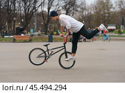 BMX in the Moscow park. Young man doing trick on the bike in the spring day. Extreme sports is very popular among youth. 2019. Редакционное фото, фотограф YuryKara / Фотобанк Лори
