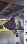 A woman performs the Bhujangasana exercise in a hammock, an inverted cobra pose, exercises in sportswear in a yoga studio. Стоковое видео, видеограф Сергей Чайко / Фотобанк Лори