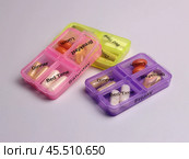 Three vitamin-filled pillboxes with a timetable for taking on a light pale lilac background. Стоковое фото, фотограф Veronika Belosokhova / Фотобанк Лори