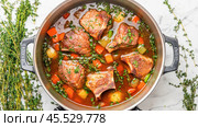 Delicious short ribs stew simmering in pot with fresh thyme and vegetables. Стоковое AI-изображение, AI-художник Юрий Поздников / Фотобанк Лори