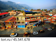 Pokhara, Nepal - November 11, 2018: Fruit merchant rides down the street in the early morning. Top view of the Phewa lake and Pokhara streets. Редакционное фото, фотограф VittoriaChe / Фотобанк Лори