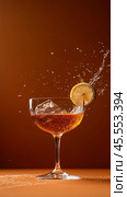Refreshing sparkling drink with ice and lemon slice splashing in glass against brown background. Стоковое AI-изображение, AI-художник Сергей Толмачёв / Фотобанк Лори