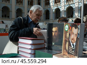 06.04.2023, Москва. Международная ярмарка интеллектуальной литературы «non/fictioNвесна» в Гостином дворе. Мужчина внимательно рассматривает книгу. Редакционное фото, фотограф Дмитрий Киселёв / Фотобанк Лори