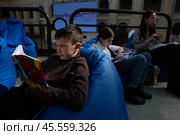 06.04.2023, Москва. Международная ярмарка интеллектуальной литературы «non/fictioNвесна» в Гостином дворе. Дети читают книги лёжа в креслах. Редакционное фото, фотограф Дмитрий Киселёв / Фотобанк Лори