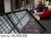 06.04.2023, Москва. Международная ярмарка интеллектуальной литературы «non/fictioNвесна» в Гостином дворе. Девушка лежит в кресле и читает книгу. Редакционное фото, фотограф Дмитрий Киселёв / Фотобанк Лори