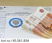 Налоговая декларация, пачка денег и конверт из налоговой службы (2024 год). Редакционное фото, фотограф Татьяна Т / Фотобанк Лори
