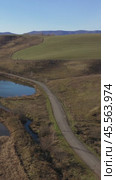 Vertical drone video of flying over a hilly rural landscape with a winding road and fish ponds. Altai Krai. Стоковое видео, видеограф Сергей Пристяжнюк (Serg Zastavkin) / Фотобанк Лори