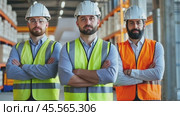 Engineers standing with arms crossed in factory wearing hardhats and safety vests. Стоковое AI-видео, аниматор Юрий Поздников / Фотобанк Лори
