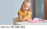 A little girl paints her cheeks with baby blush. The child draws with children's cosmetics. A daughter imitates her mother. Стоковое фото, фотограф Кутина Татьяна / Фотобанк Лори