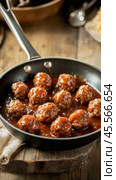 Delicious bbq meatballs simmering in tomato sauce in a frying pan. Стоковое AI-изображение, AI-художник Юрий Поздников / Фотобанк Лори