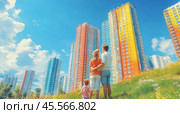 A young family with a child is standing in a meadow near a large apartment building after buying a new apartment and enjoying a new life. Стоковое AI-изображение, AI-художник Ярославский Максим / Фотобанк Лори