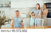 Irritated dissatisfied woman yelling at confused husband in home kitchen. Two frustrated teenage girls sitting at table during parental quarrel, selective focus. Стоковое видео, видеограф Яков Филимонов / Фотобанк Лори