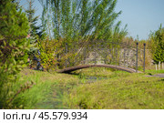 Semicircular metal bridge over a stream (2024 год). Стоковое фото, фотограф Evgenii Predibailo / Фотобанк Лори