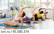 Fit girl performing side stretch in lotus pose during yoga practice. Стоковое фото, фотограф Яков Филимонов / Фотобанк Лори