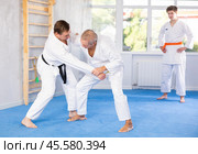 Judo or jiu jitsu classes - two men of different age practicing grabbing and throwing on sports mats. Стоковое фото, фотограф Яков Филимонов / Фотобанк Лори