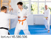 Concentrated guy honing punching techniques during kumite at karate training. Стоковое фото, фотограф Яков Филимонов / Фотобанк Лори