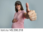 Happy and cheerful young pregnant woman in a baseball cap. Стоковое AI-изображение, AI-художник Дмитрий Киселёв / Фотобанк Лори