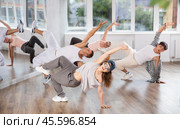Girl and her students perform hip hop dance on one bent leg, movement in horizontal plane near floor. Стоковое фото, фотограф Яков Филимонов / Фотобанк Лори