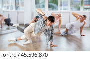 Man and his students perform hip hop dance on one bent leg, movement in horizontal plane near floor. Стоковое фото, фотограф Яков Филимонов / Фотобанк Лори