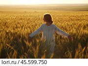 Happy young woman among field at sunset. Стоковое фото, фотограф Дмитрий Киселёв / Фотобанк Лори