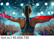 A young athlete stands proudly with arms outstretched, breaking the finish line ribbon amidst a joyous crowd illuminated by bright lights, marking a triumphant moment. Стоковое AI-изображение, AI-художник Sergey Grishin / Фотобанк Лори