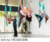Active young Latin female performing Aerial yoga exercise or antigravity yoga indoor. Pilates, stretch, balance, healthy lifestyle. Стоковое фото, фотограф Яков Филимонов / Фотобанк Лори