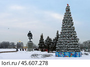 Город Тверь, Тверская область, Россия. Рождественская ель около памятника Афанасию Никитину на берегу реки Волги. Вдали Спасо-Преображенский собор. Около памятника группа туристов на экскурсии. Осмотр достопримечательностей Твери. Зимнее путешествие во время новогодних каникул. Холодная зимняя погода. Много снега. На основании новогодней ёлки надписи «С Новым годом!». Редакционное фото, фотограф Андрей Степанов / Фотобанк Лори