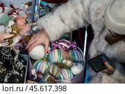 Женщина выбирает елочные игрушки во время предпраздничные распродажи новогодних товаров в Главном универсальном магазине (ГУМ) в центре города Москвы, Россия. Редакционное фото, фотограф Николай Винокуров / Фотобанк Лори