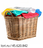 Wicker laundry basket overflowing with colorful clothes and towels. Стоковое AI-изображение, AI-художник Иван Рябоконь / Фотобанк Лори