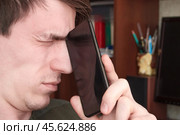 Парень крепко зажмурил глаза, после разговора по смартфону. Стоковое фото, фотограф Vladislav_v / Фотобанк Лори