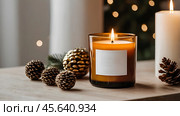 A mock-up of a cozy burning candle made of amber glass with an empty white label in a festive, New Year's home interior. Стоковое AI-изображение, AI-художник Photojuli / Фотобанк Лори