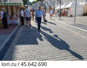 Город Витебск, Беларусь. Уличная торговля на улице Толстого. Прохожие отбрасывают длинные тени (2024 год). Редакционное фото, фотограф Наталья Николаева / Фотобанк Лори