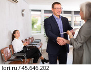 Middle-aged man handshaking with other person in waiting room. Стоковое фото, фотограф Яков Филимонов / Фотобанк Лори