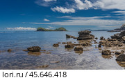 The time of low tide in the ocean. Littoral. Clams were attached to exposed boulders. The bottom is visible through the clear water. A beautiful island on the horizon against the blue sky and clouds. Стоковое фото, фотограф Вера Ивановна Кубарева / Фотобанк Лори