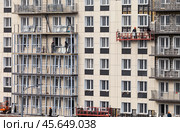 ANGARSK, IRKUTSK REGION, RUSSIA - October 08, 2024: Builders work on a high-rise residential building: tiling the facade, glazing balconies and windows. Housing construction concept. Редакционное фото, фотограф Виктория Катьянова / Фотобанк Лори