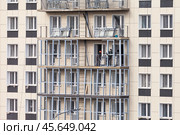 ANGARSK, IRKUTSK REGION, RUSSIA - October 08, 2024: Builders work on a high-rise modern residential building and glazing balconies. Housing construction concept. Редакционное фото, фотограф Виктория Катьянова / Фотобанк Лори