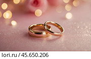 Gold wedding rings on a pink background with a side. Wedding rings. The wedding day. The newlyweds. Стоковое AI-изображение, AI-художник Photojuli / Фотобанк Лори