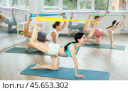 Girl leads class women, standing on all fours, performing exercises with wide elastic skip rope. Стоковое фото, фотограф Яков Филимонов / Фотобанк Лори