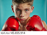A boy in boxing gloves strikes, a cute teenage boy stands in a fighter's pose, ready to fight. Playing sports. Children's sports sections. Стоковое AI-изображение, AI-художник Photojuli / Фотобанк Лори